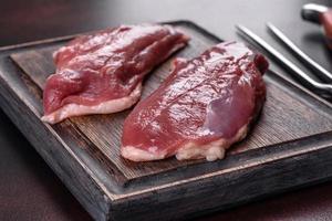 Raw duck breast with herbs and spices on a dark concrete background photo