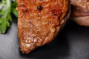 Baked duck breast with herbs and spices on a dark concrete background photo