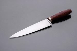 Un gran cuchillo de caza artesanal acostado sobre un fondo oscuro foto
