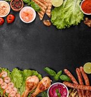 Composition of sausages, chicken, pork and shrimp prepared on grill, as well as vegetables prepared on grill with spices and herbs photo