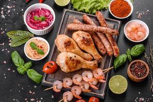 Composition of sausages, chicken, pork and shrimp prepared on grill, as well as vegetables prepared on grill with spices and herbs photo