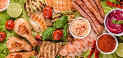 composición de salchichas, pollo, cerdo y camarones preparados a la parrilla, así como verduras preparadas a la parrilla con especias y hierbas foto