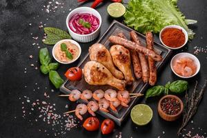 Composition of sausages, chicken, pork and shrimp prepared on grill, as well as vegetables prepared on grill with spices and herbs photo