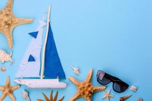 Glasses and hat with shells and sea stars on a colored background photo