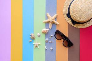 Gafas y sombrero con conchas y estrellas de mar sobre un fondo de color foto