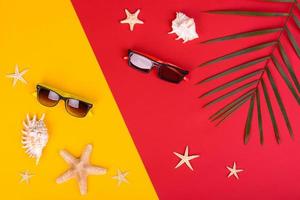 Glasses and hat with shells and sea stars on a colored background photo