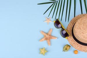 Fruit carambol, beach accessories and foliage of a tropical plant on colored paper photo