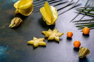 Fruit carambol, beach accessories and foliage of a tropical plant on colored paper photo