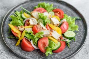 Fresh delicious salad with chicken, tomato, cucumber, onions and greens with olive oil photo