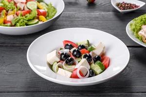 Fresh delicious Greek salad with tomato, cucumber, onions and olives with olive oil