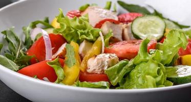 Fresh delicious salad with chicken, tomato, cucumber, onions and greens with olive oil photo