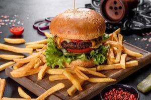 Delicious fresh burger with beef cutlet, tomatoes and lettuce with french fries photo