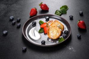 Tasty baked pancakes with berries and mint with powdered sugar and topping on a gray plate photo