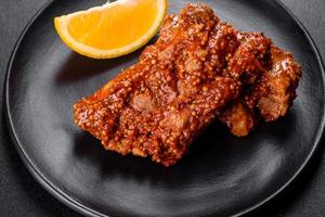 Delicious fresh baked pork ribs with orange on a black plate photo