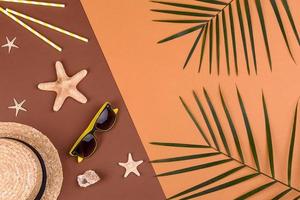 Beach accessories, glasses and hat with shells and sea stars on a colored background. Summer background photo