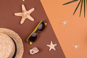 Beach accessories, glasses and hat with shells and sea stars on a colored background. Summer background photo