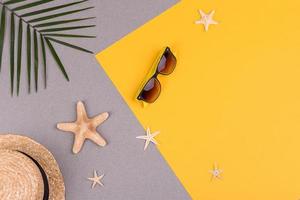 accesorios de playa, gafas y sombrero con conchas y estrellas de mar sobre un fondo de color. fondo de verano foto