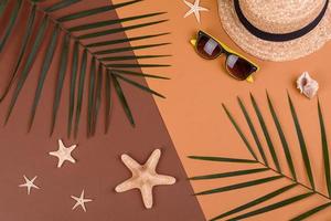 Beach accessories, glasses and hat with shells and sea stars on a colored background. Summer background photo