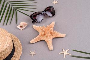 Beach accessories, glasses and hat with shells and sea stars on a colored background. Summer background photo