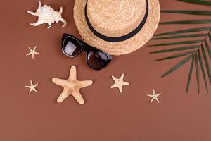 accesorios de playa, gafas y sombrero con conchas y estrellas de mar sobre un fondo de color. fondo de verano foto