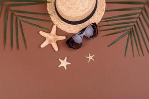 accesorios de playa, gafas y sombrero con conchas y estrellas de mar sobre un fondo de color. fondo de verano foto