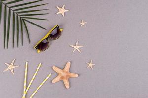 accesorios de playa, gafas y sombrero con conchas y estrellas de mar sobre un fondo de color. fondo de verano foto