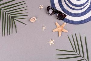 Beach accessories, glasses and hat with shells and sea stars on a colored background. Summer background photo