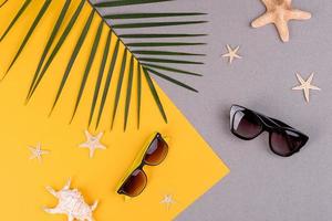 Beach accessories, glasses and hat with shells and sea stars on a colored background. Summer background photo