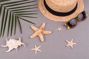 accesorios de playa, gafas y sombrero con conchas y estrellas de mar sobre un fondo de color. fondo de verano foto