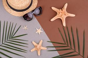 Beach accessories, glasses and hat with shells and sea stars on a colored background. Summer background photo