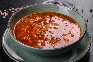 Delicious fresh hot borsch with tomato and meat in a ceramic plate photo