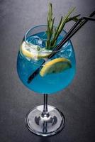 Cóctel alcohólico curacao azul con hielo, limón y tubos de cóctel foto