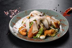 Delicious fresh caesar salad with chicken meat, breadcrumbs, tomatoes and lettuce leaves photo