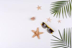 Beach accessories, glasses and hat with shells and sea stars on a colored background photo