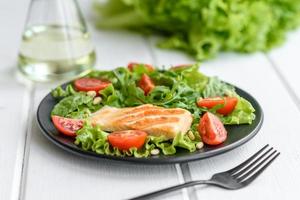 deliciosa ensalada fresca con pescado, tomates y hojas de lechuga foto