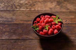 Deliciosas frambuesas rojas jugosas frescas sobre una mesa oscura foto