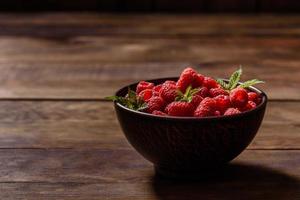 Deliciosas frambuesas rojas jugosas frescas sobre una mesa oscura foto