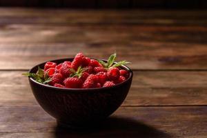 Deliciosas frambuesas rojas jugosas frescas sobre una mesa oscura foto