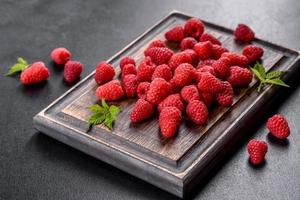 Deliciosas frambuesas rojas jugosas frescas sobre una mesa oscura foto