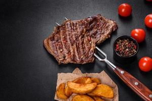 Delicious juicy fresh beef steak with spices and herbs on a dark concrete background photo