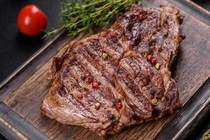 Delicious juicy fresh beef steak with spices and herbs on a dark concrete background photo