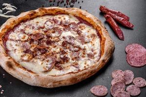 Deliciosa pizza italiana fresca con cuatro tipos de carne sobre un fondo de hormigón oscuro foto