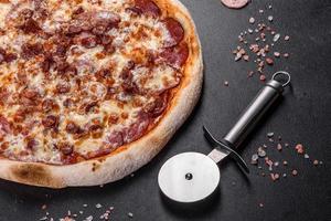 Deliciosa pizza italiana fresca con cuatro tipos de carne sobre un fondo de hormigón oscuro foto