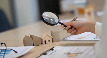 Woman with magnifying glass over a wooden house photo