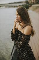 Young long hair brunette woman standing on the riverside photo