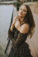 Young long hair brunette woman standing on the riverside photo