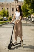 Mujer joven montando un scooter eléctrico en una calle foto