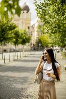 Mujer joven con un teléfono móvil mientras camina por la calle foto