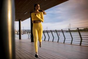 Mujer joven haciendo ejercicio para correr por el paseo fluvial foto