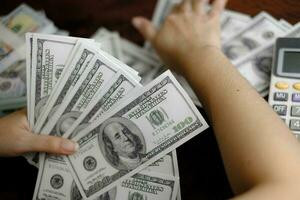 hombres de negocios mujeres contando dinero en una pila de billetes de 100 dólares estadounidenses mucho dinero foto